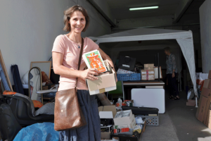 Eine Frau bringt Bücher für den Gratisflohmarkt in Magdeburg